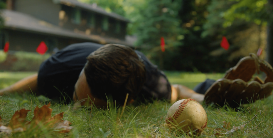 A man laying on the ground next to a baseball after being shocked by a dog fence.
