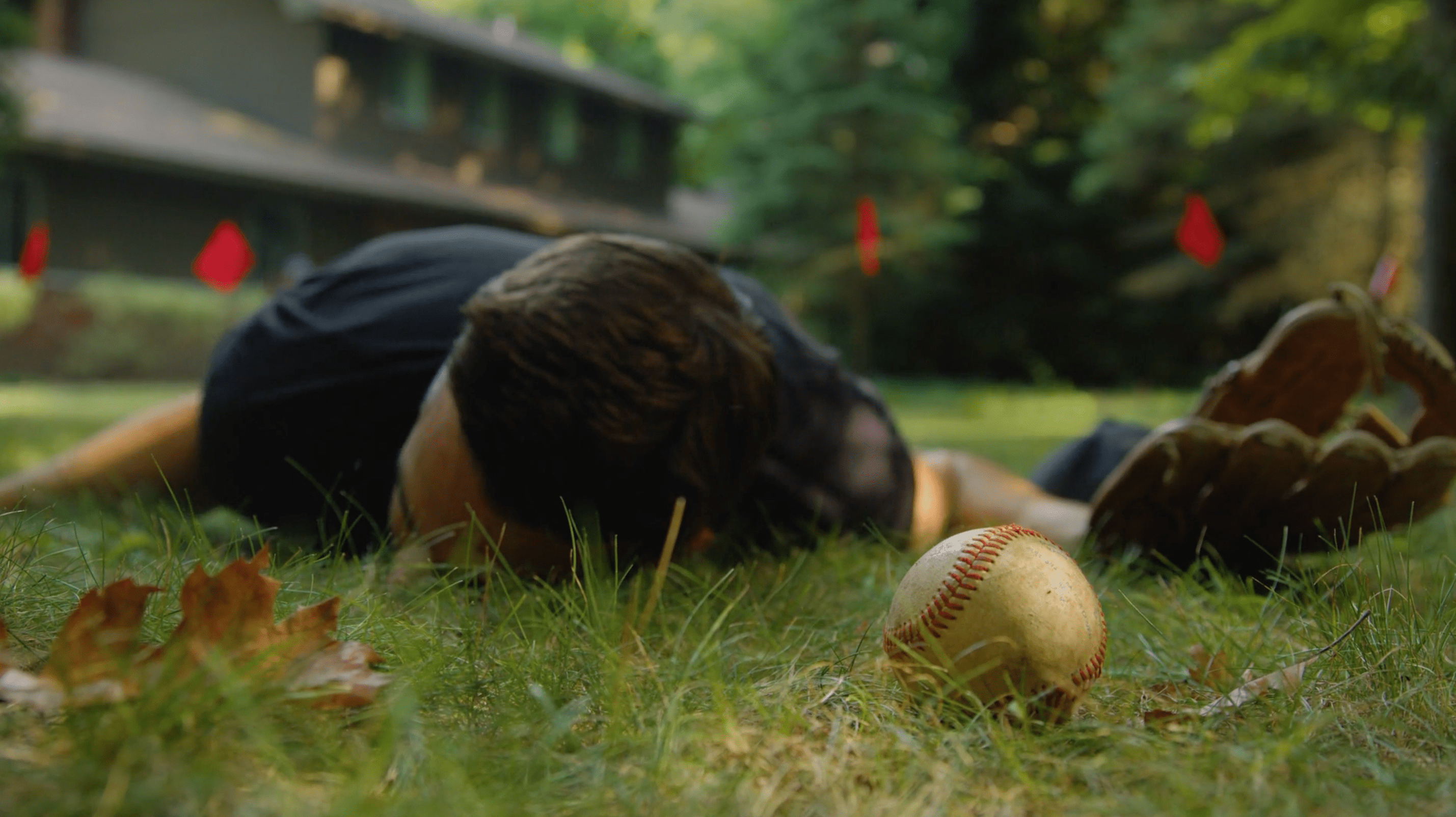A man laying on the ground next to a baseball after being shocked by a dog fence.